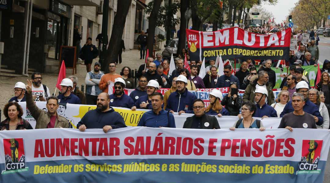 Fotografia de uma grande manifestação da CGTP em Lisboa, com uma multidão de trabalhadores e bandeiras vermelhas.
